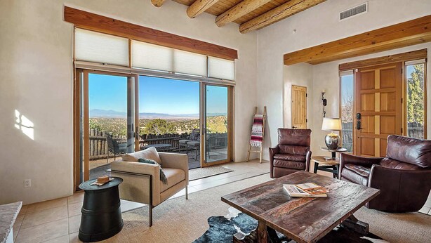 A spacious living room with a large sliding glass door leading to a patio, leather furniture, and a rustic wooden table.