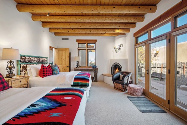 A bedroom with a large bed, a fireplace, a window, and a view of the outside. - Breathtaking Sunset Views, Community Pool (Santa Fe)