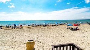 A sandy beach with umbrellas and people. - Beachfront Condo | Ocean Breeze & Resort Pool (Hollywood)