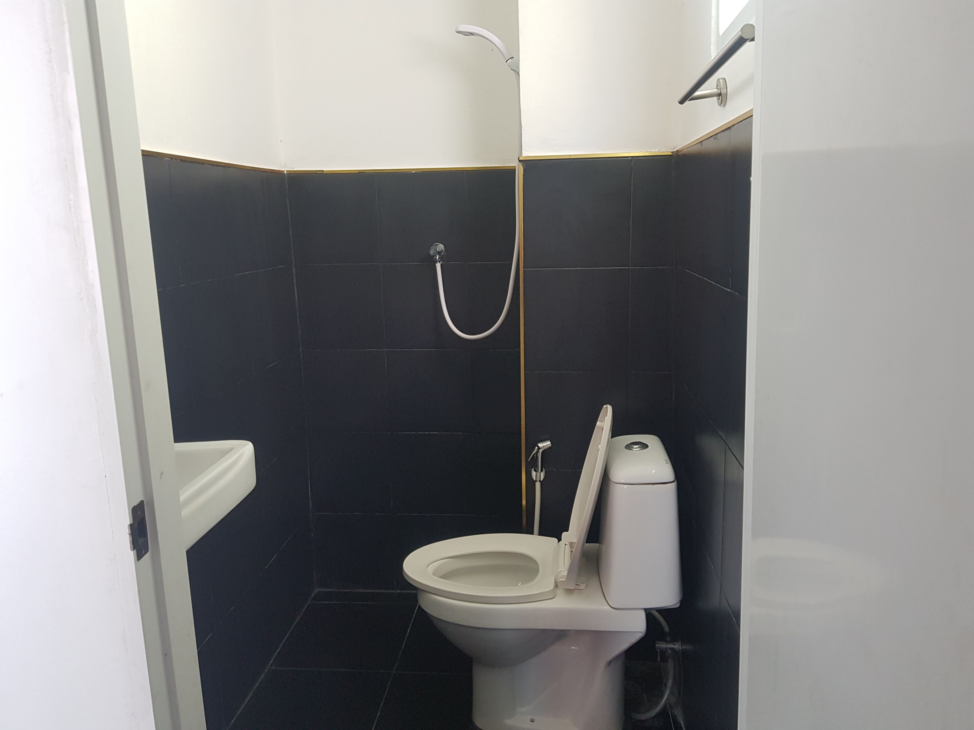 A small, compact bathroom with a toilet, a shower, and a hand dryer.