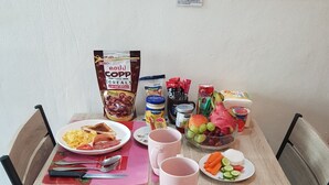 A breakfast table set with plates of scrambled eggs, toast, and sausages, along with cups and condiments. - Sam's Place (Bangkok)