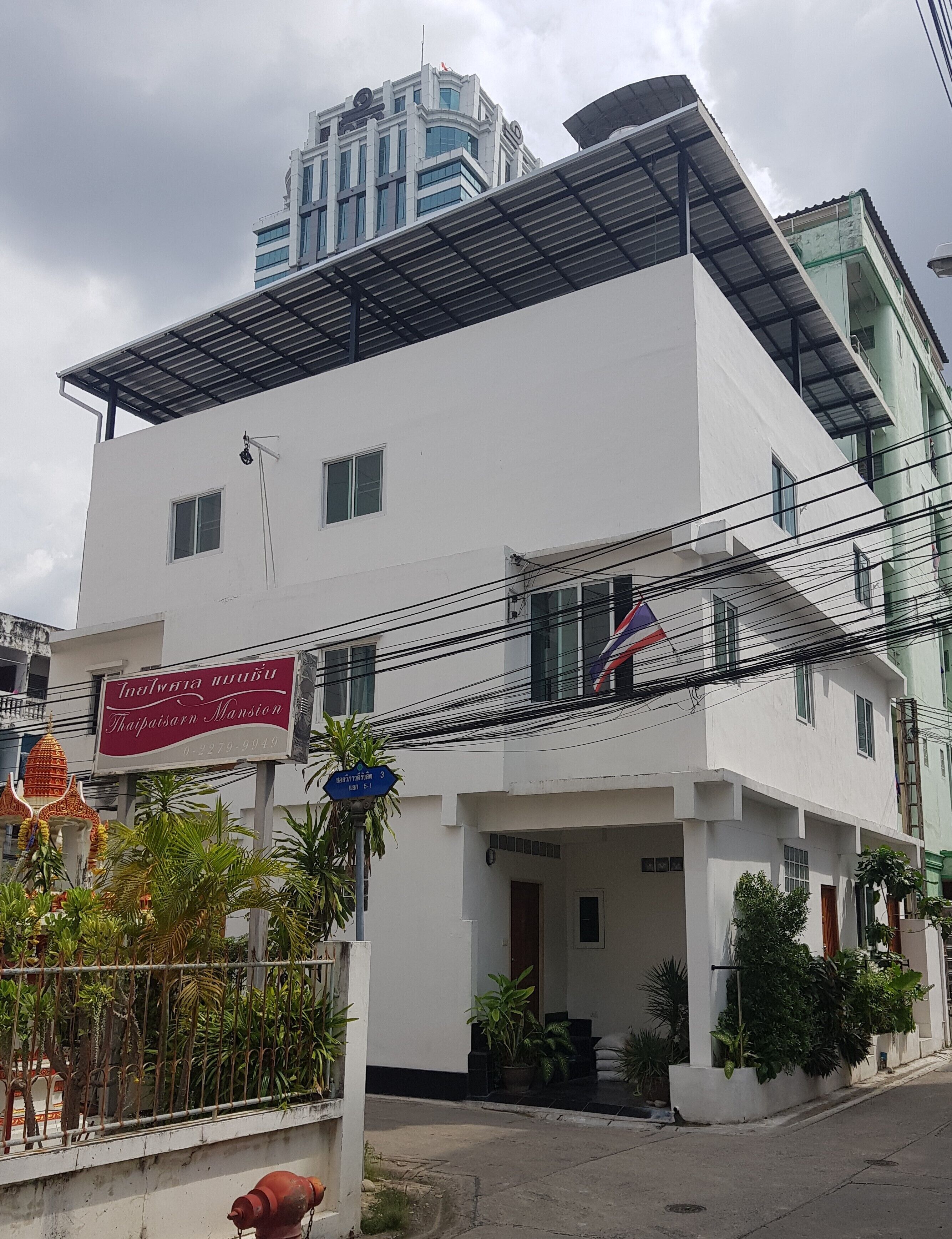 A modern white building with a sign for 'Inthavarana Mansion' and a blue sign indicating the address.