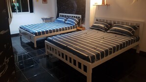 A bedroom with two beds, a window, a nightstand, and a wall-mounted shelf with a decorative item. - Sam's Place (Bangkok)