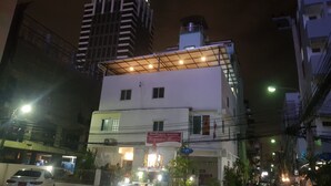 A multi-story building with a flat roof and a sign indicating a restaurant on the ground floor. - Sam's Place (Bangkok)
