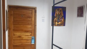 A wooden door with a number '5' above it, a small sign on the door, and a staircase with a metal railing leading to a higher floor. - Sam's Place (Bangkok)