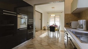 Une cuisine moderne avec un coin repas, comprenant un grand îlot central, des appareils électroménagers intégrés et une vue sur la salle à manger.