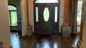 A spacious foyer with a dark wooden door, stone accents, and a chandelier. - Family Home (Water Valley)