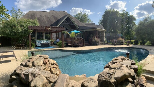 A backyard with a swimming pool, a pergola, and a covered patio area. - Family Home (Water Valley)