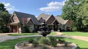 A large house with a stone driveway, a fountain in the front yard, and a well-maintained lawn. - Family Home (Water Valley)