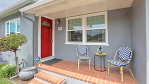 A house with a red door, two chairs, a small table, and a number 532 sign.