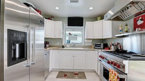 A modern kitchen with stainless steel appliances, white cabinetry, and a built-in oven.