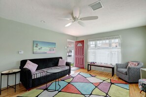 Ein Wohnzimmer mit Sofa, Sessel, Couchtisch und einem farbenfrohen Teppich.