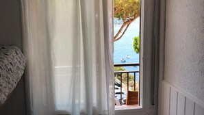 Una habitación con ventana que da a una masa de agua, una silla y una cama.