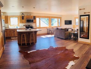 Kitchen area with central island, stools, sofa, and coffee table.