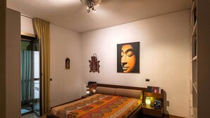 Um quarto com uma cama grande, uma mesa de cabeceira, uma luminária na parede e um quadro.