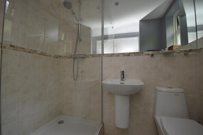 Bathroom features a glass-enclosed shower, pedestal sink, and toilet.