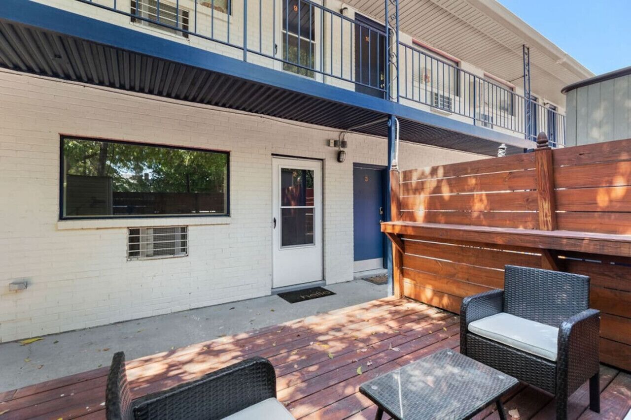 A two-story building with a balcony, a wooden deck, and outdoor seating.
