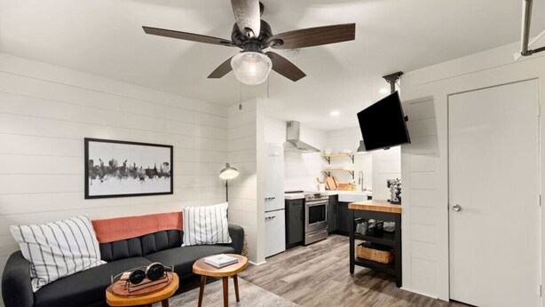 A modern living room with a black sofa, a coffee table, and a ceiling fan.