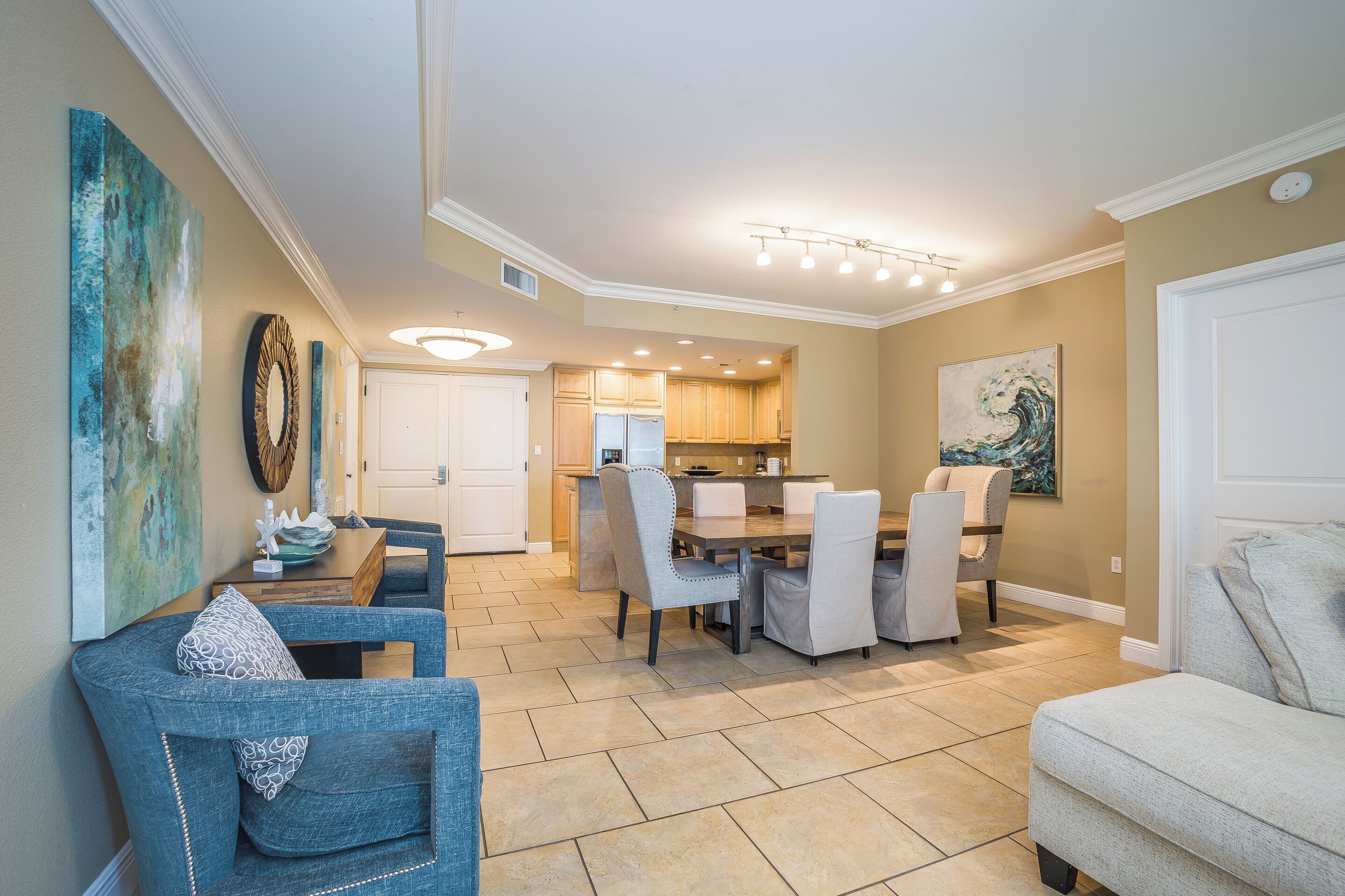 A spacious living area with a dining table, chairs, and a kitchen in the background.