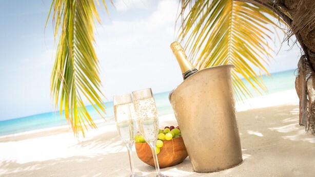 A beach scene with a bucket, two glasses, and a bottle of champagne.