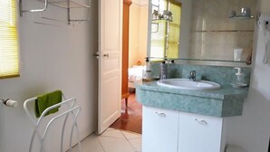Casa de banho com lavatório branco, espelho de vidro e porta-toalhas com toalha verde.