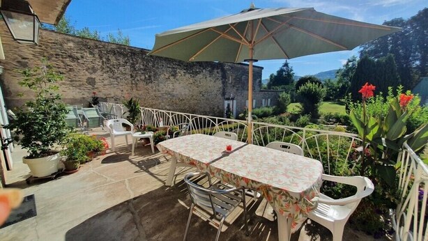 An outdoor patio with a table and chairs, surrounded by potted plants and a stone wall. - Double Room Queen Size with Garden View (REMONCOURT)