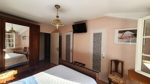 A bedroom with a bed, a chair, a desk, a television, and a wardrobe. - Double Room Queen Size with Garden View (REMONCOURT)