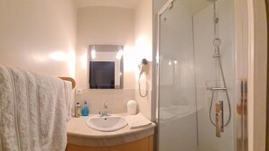 A bathroom with a sink, mirror, towel, and a glass shower enclosure. - Double Room Queen Size with Garden View (REMONCOURT)