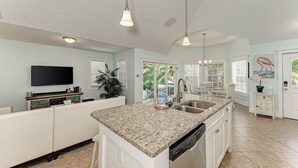 A spacious kitchen with a granite countertop, a built-in dishwasher, and a large island with a sink.