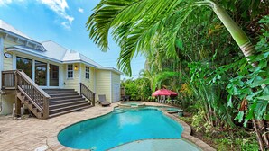 A house with a swimming pool surrounded by lush greenery.