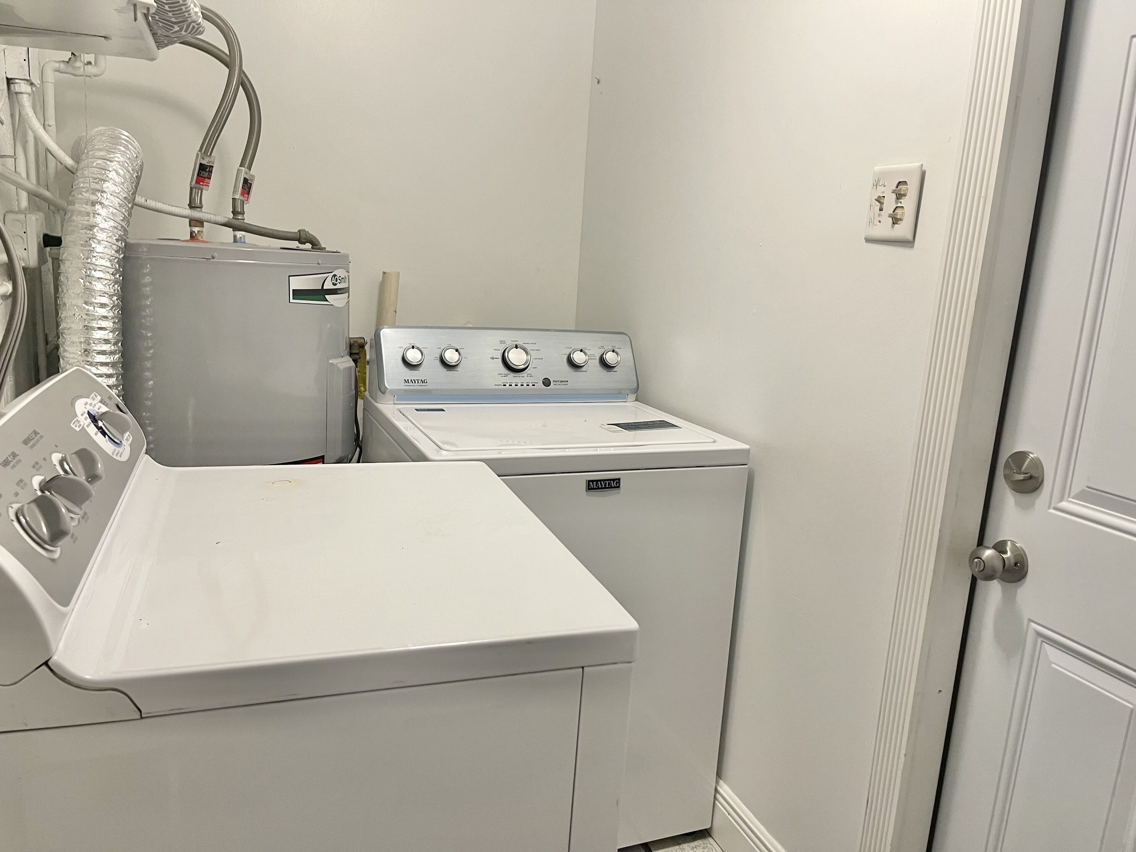 Lavanderia dotata di lavatrice e asciugatrice Maytag, un lavandino e un tubo di scarico.