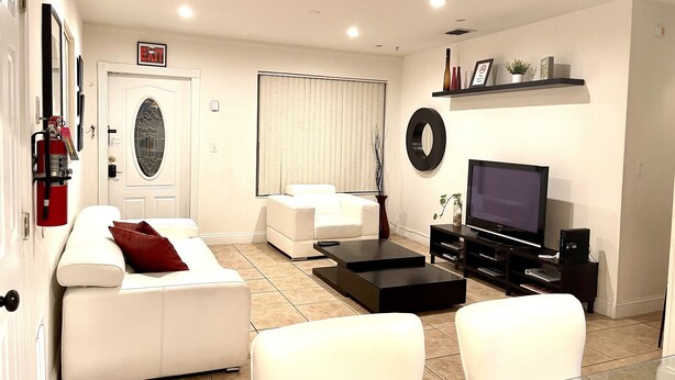 A living room with a white sofa, a black coffee table, a TV, and a fireplace.