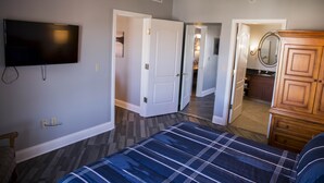 A bedroom with a bed, a TV mounted on the wall, and a wooden dresser. - Top floor, BEST view, Viera condo at Lake Las Vegas! (Henderson)