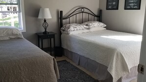 Una camera da letto con due letti, un comodino con lampada, un tappeto decorato e una finestra vista esterna.