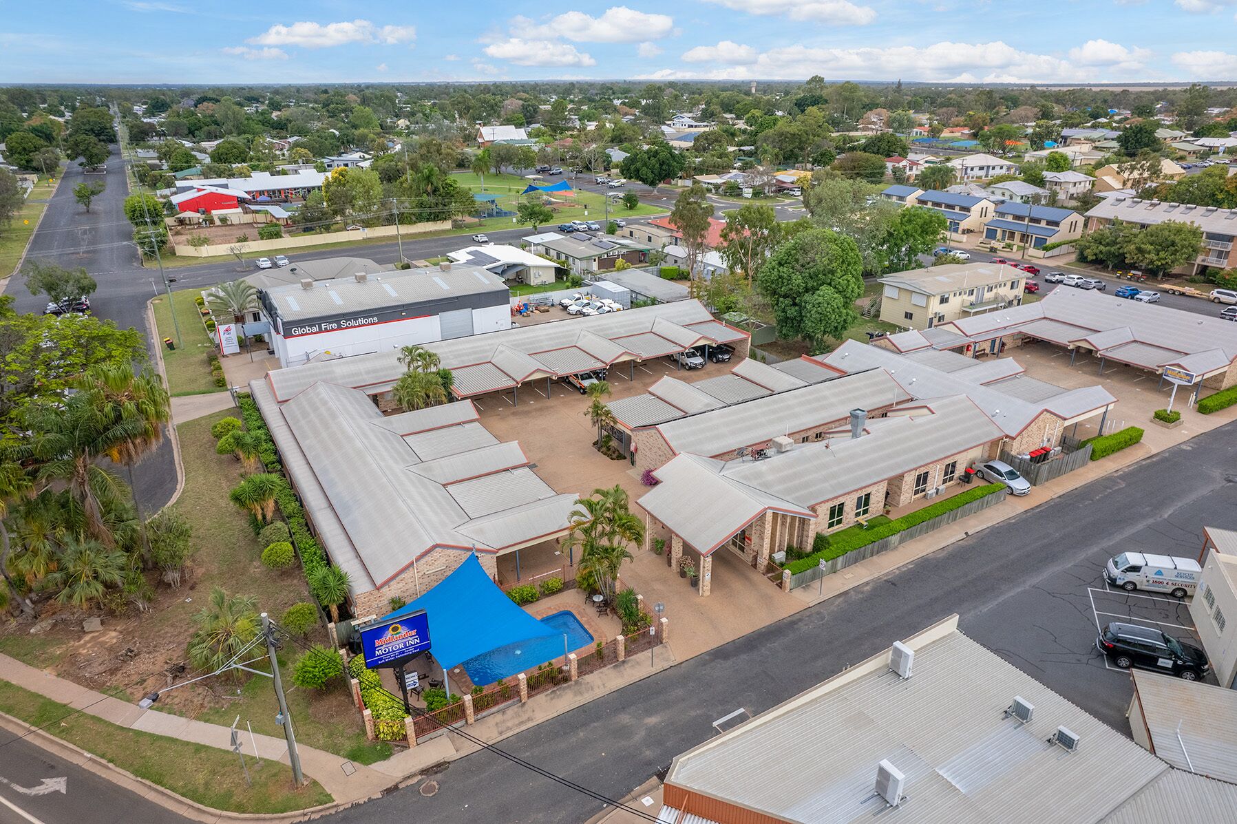 A commercial area with multiple buildings, including a Global Fire Solutions facility and a motel with a pool.