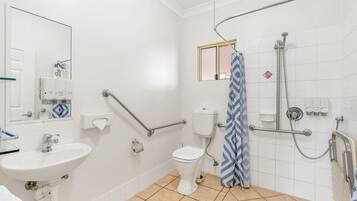 A bathroom with a white sink, toilet, and shower area.