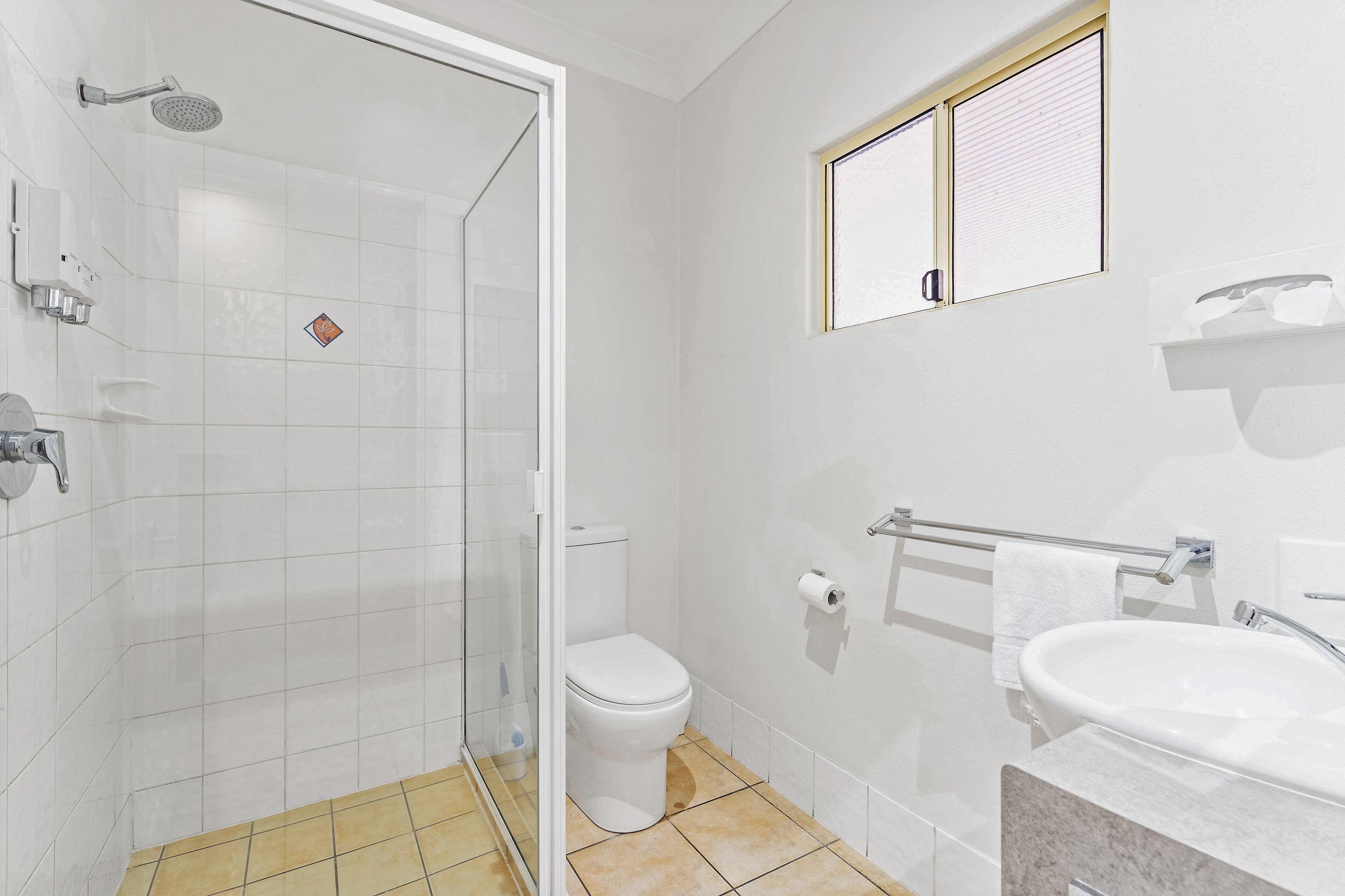 Un baño moderno con cabina de ducha de vidrio, inodoro, lavabo y toallero.