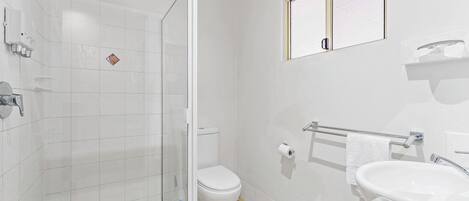 Un baño moderno con cabina de ducha de vidrio, inodoro, lavabo y toallero.
