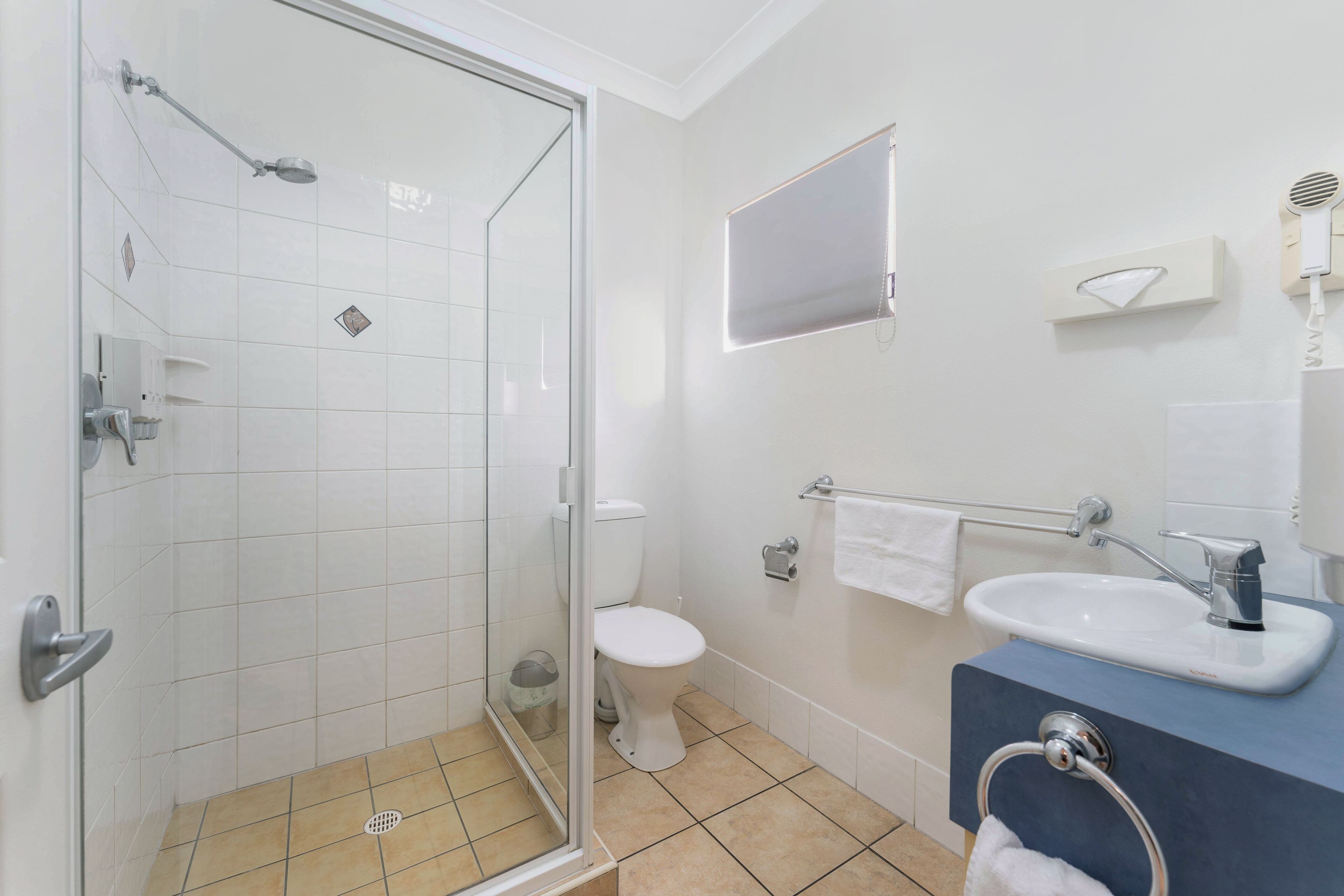 Un baño con cabina de ducha de vidrio, inodoro, lavamanos y perchero para toallas.