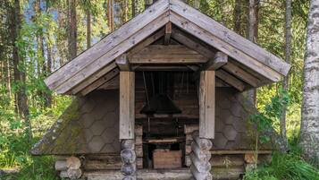 Une cabane rustique en bois, dotée d’un toit à deux versants, d’une cheminée et de fondations en rondins.
