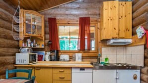 A compact kitchen with wooden cabinets, a microwave, a toaster, and a sink. - Lemmenmaja by Interhome (Juva)