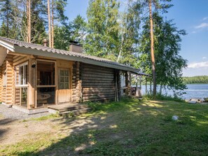 A log cabin with a porch, a deck, and a view of a lake. - Lemmenmaja by Interhome (Juva)