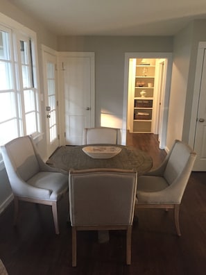 Un comedor con una mesa redonda, cuatro sillas y un armario empotrado con estantes.