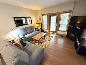 A living room with a sofa, a coffee table, a television, and a fireplace.