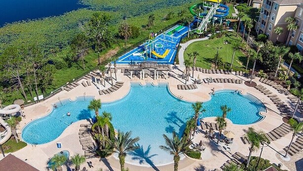 Un resort con una piscina grande, parque acuático y palmeras.