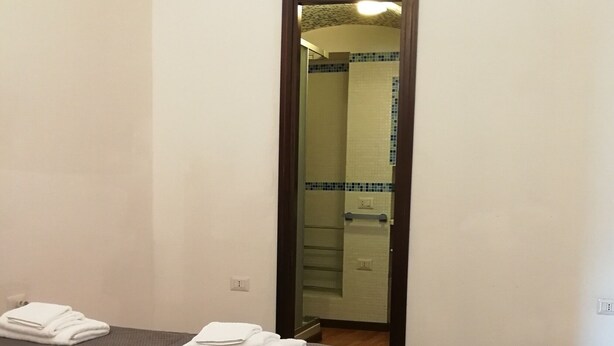 Een hotelkamer met een bed, een nachtkastje en een badkamer zichtbaar door een geopende deur.