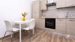 Eine moderne Küche mit hellen Holzschränken, einer weißen Arbeitsplatte und einem schwarzen Backofen.