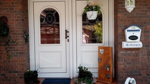 A brick house with a white door, a small porch, and a mailbox. - Lovingly furnished apartment is looking forward to young and old guests.  (Friedeburg)