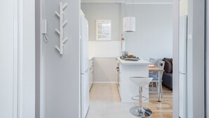 Una cocina moderna con armarios blancos, una isla central y un comedor con un taburete de bar.