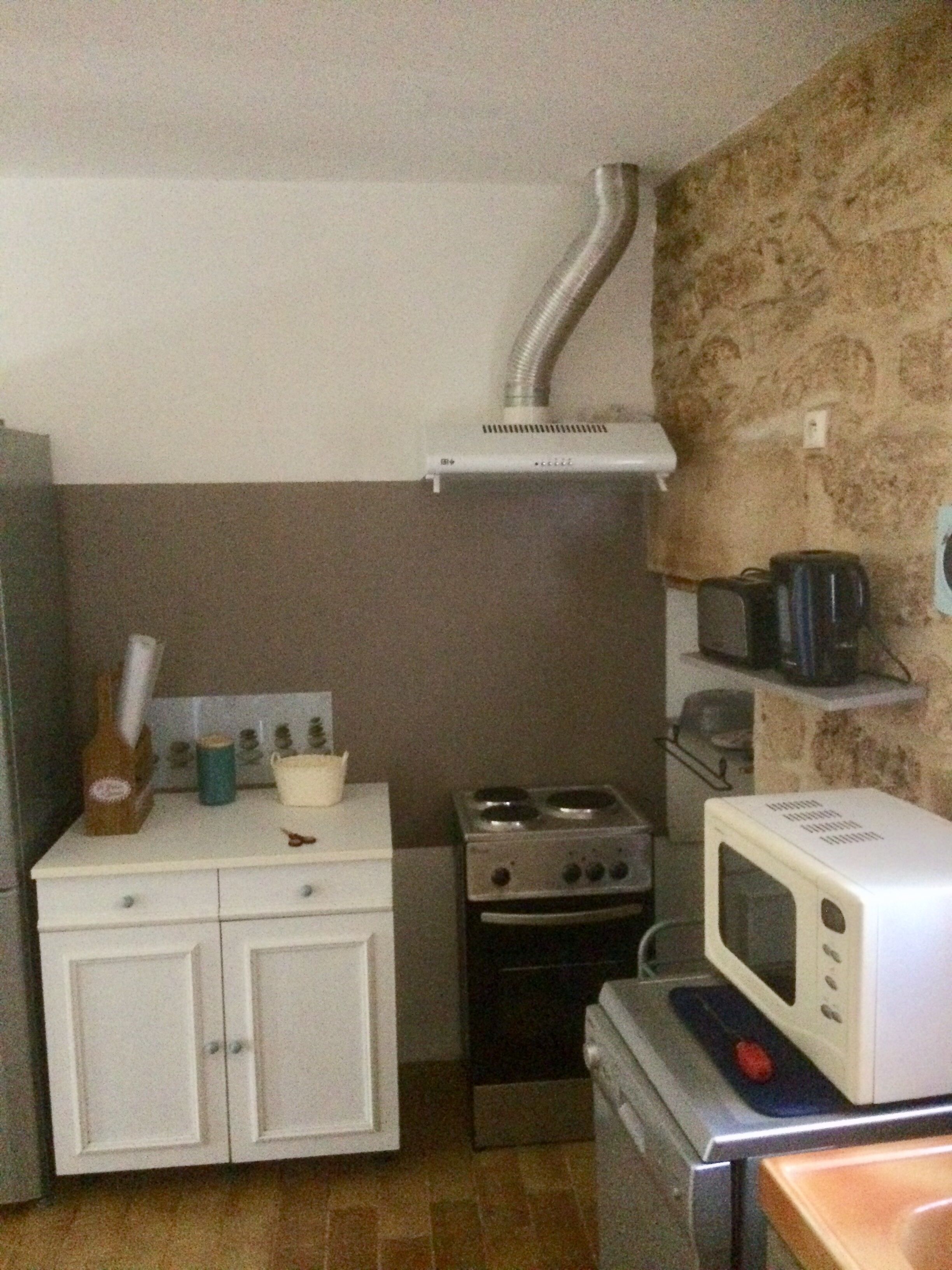 Ett kompakt kök med en spis, mikrovågsugn och ett litet skåp.